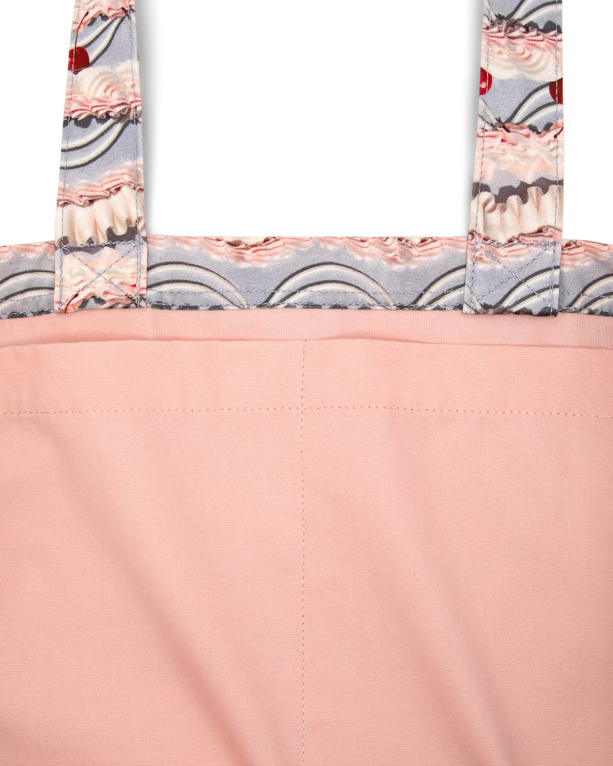 Close-up of the inside pink fabric tote bag with frosting-patterned handles on a white background.