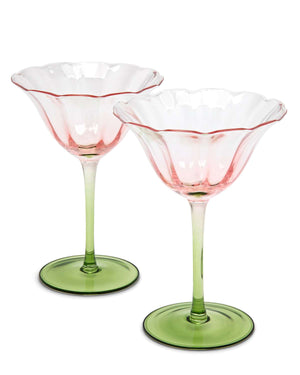 Two cocktail tulip shaped glasses with green colored base on a white surface