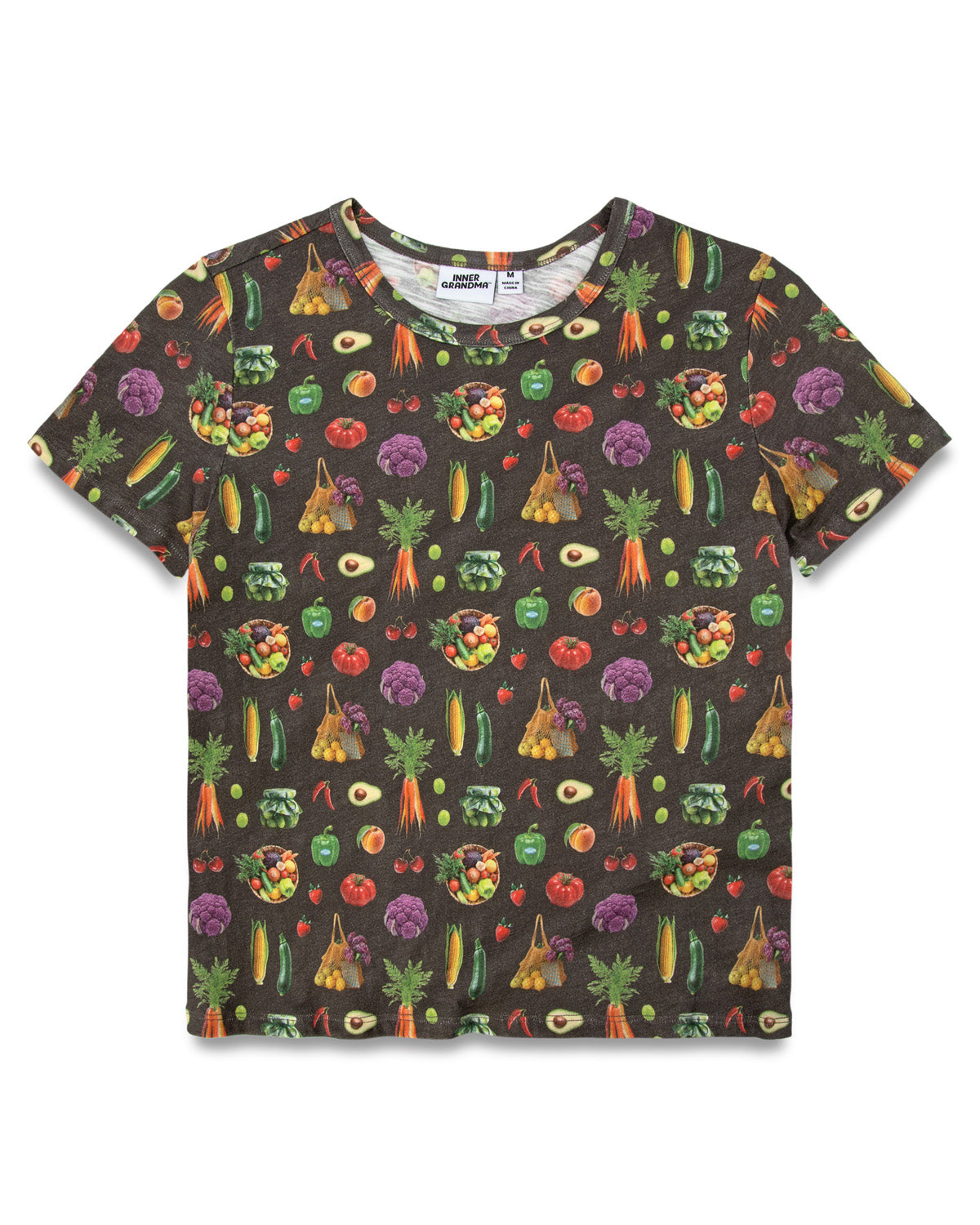 A short-sleeve dark charcoal colored t-shirt featuring an all-over vegetable print. The pattern includes various illustrated vegetables like carrots, broccoli, tomatoes, and avocados in bright colors.