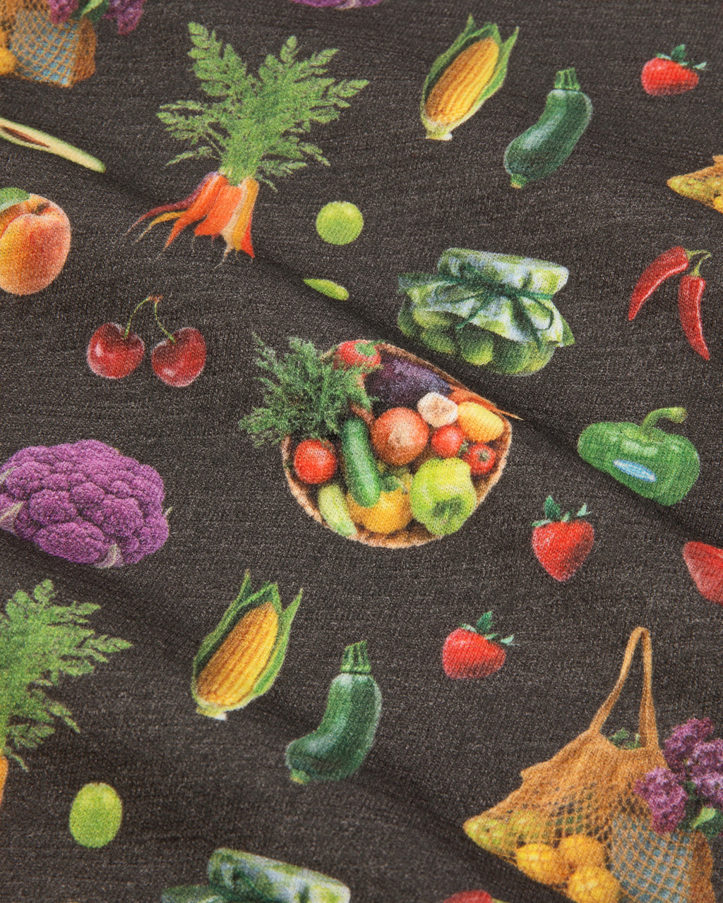 Dark gray fabric featuring a colorful all-over print of various vegetables including carrots, corn, peppers, tomatoes, broccoli, and a basket of mixed produce.