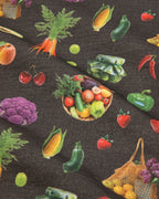 Dark gray fabric featuring a colorful all-over print of various vegetables including carrots, corn, peppers, tomatoes, broccoli, and a basket of mixed produce.