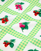close up of green and white gingham fabric with strawberries and raspberries. 
