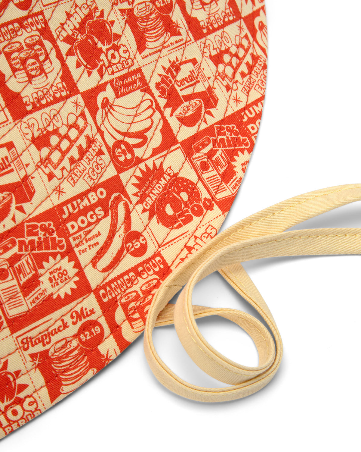 Close up of orange and beige printed sun hat with coupons of different fruits on it. 