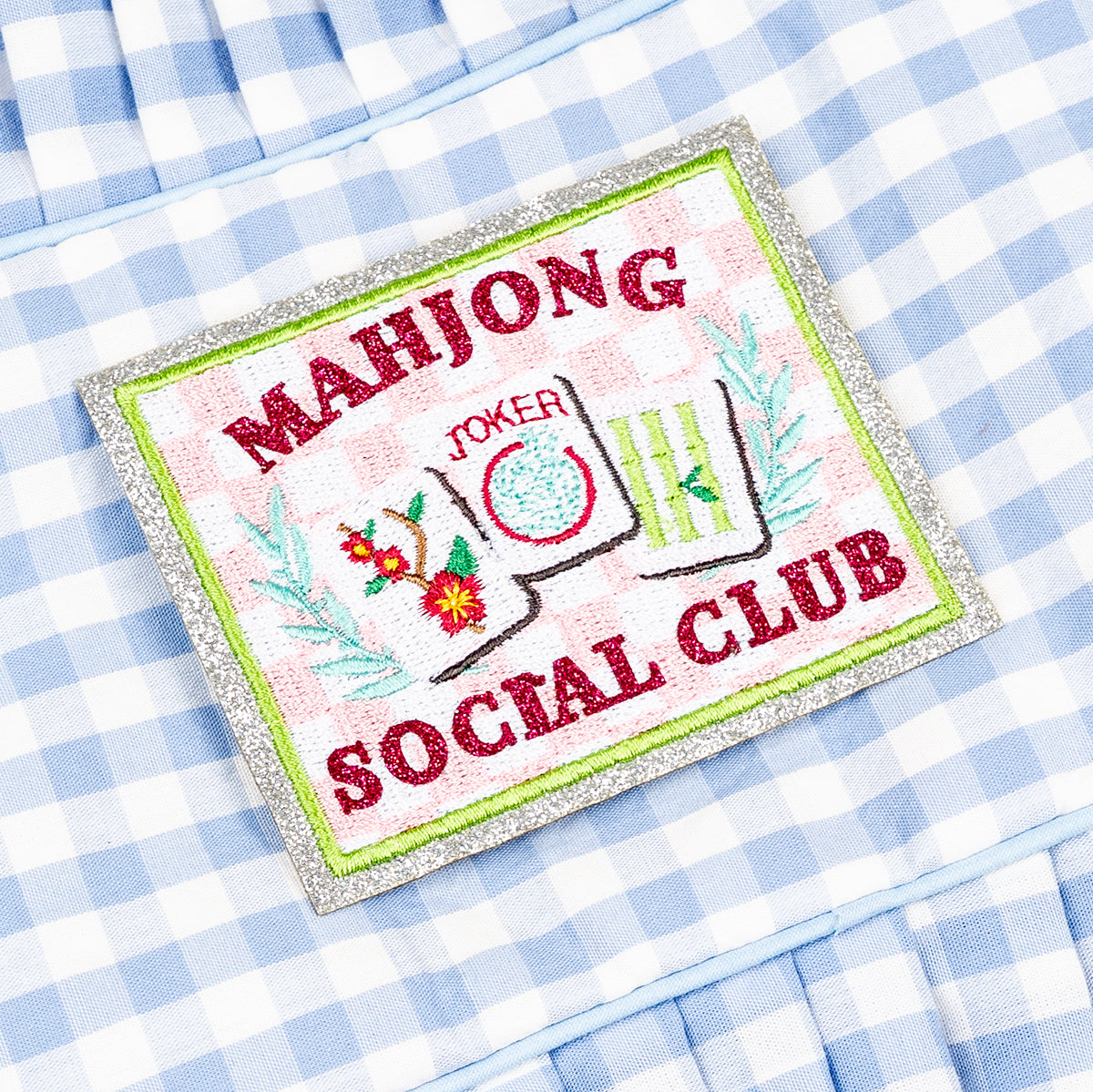 Embroidered patch with 'Mahjong Joker Social Club' design on a checkered fabric background