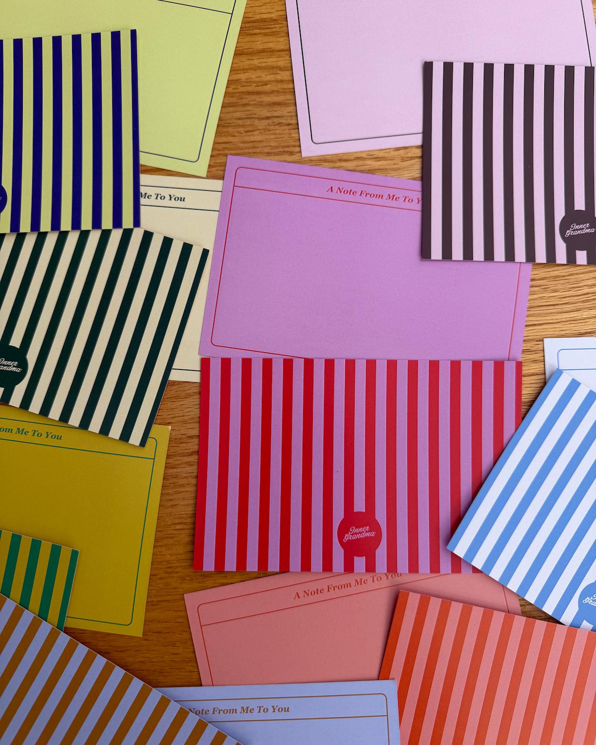 Collection of colorful stationery items including cards and envelopes on a wooden surface.