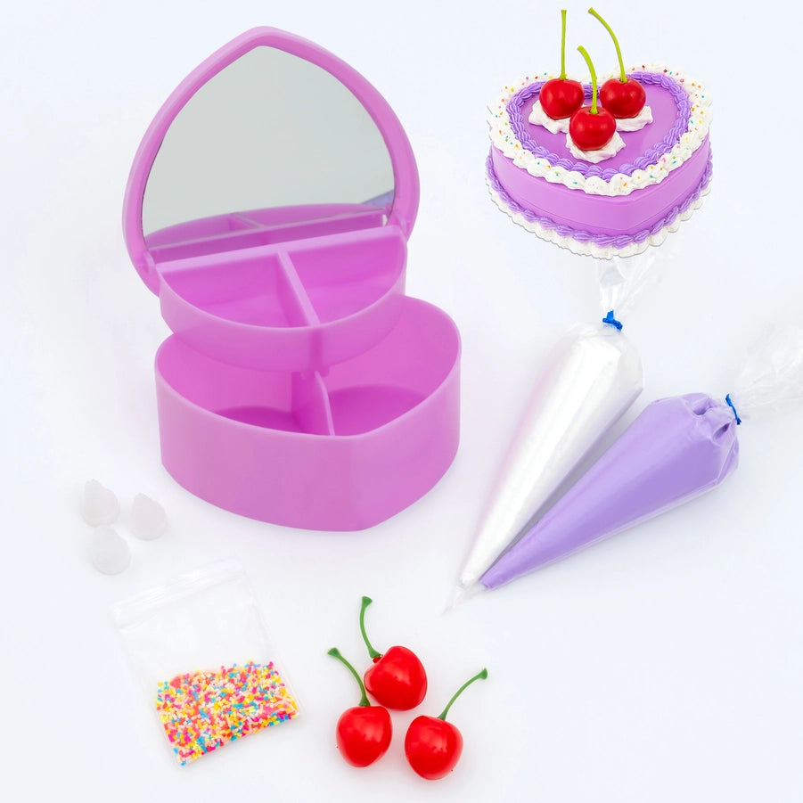 Purple heart-shaped jewelry box with cake decorating tools on a white background