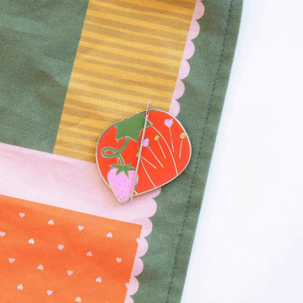 Colorful fabric with a heart-shaped brooch featuring a tomato design.