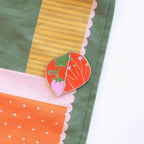 Colorful fabric with a heart-shaped brooch featuring a tomato design.