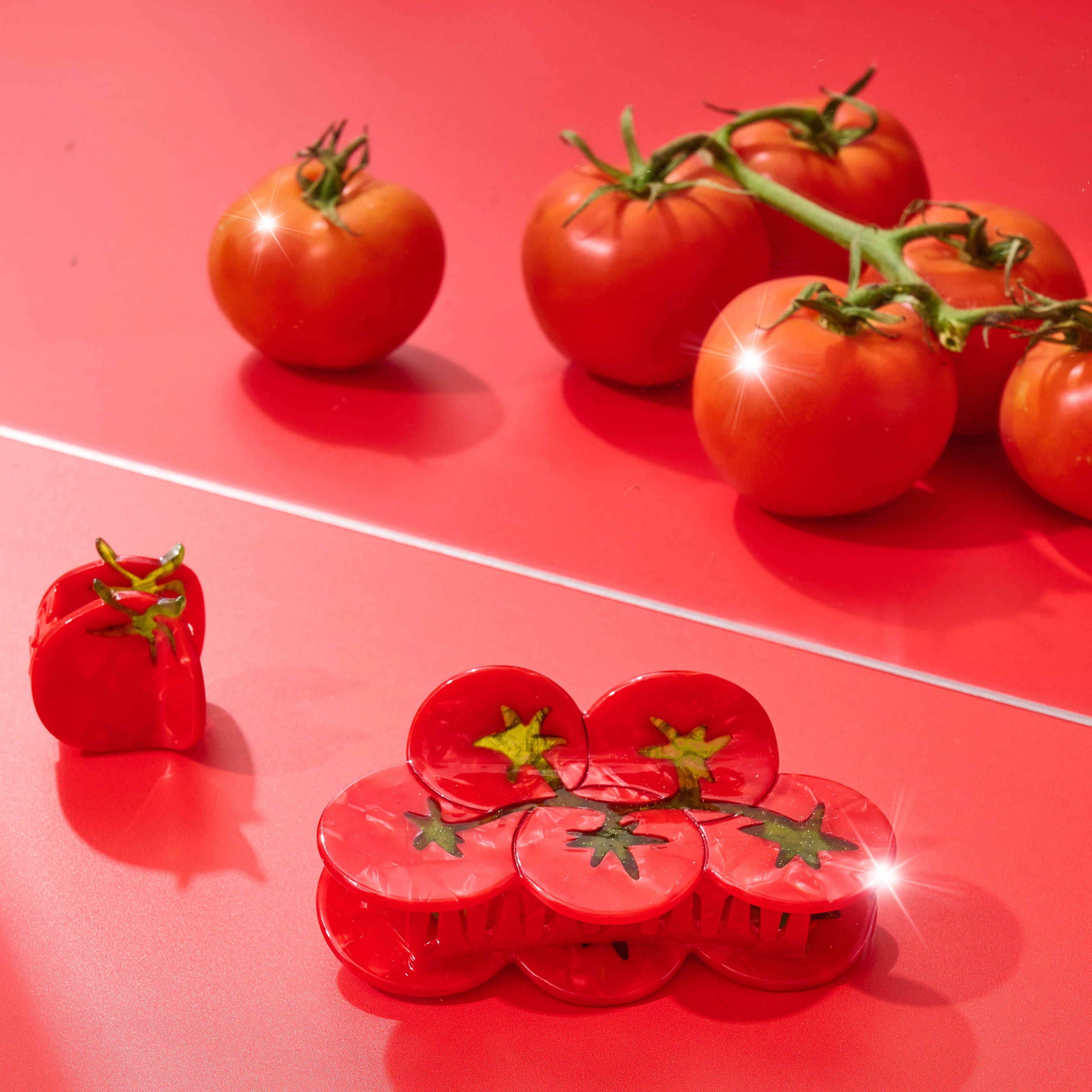 Red tomatoes on a red surface with a hair claw clip shaped like a tomato.