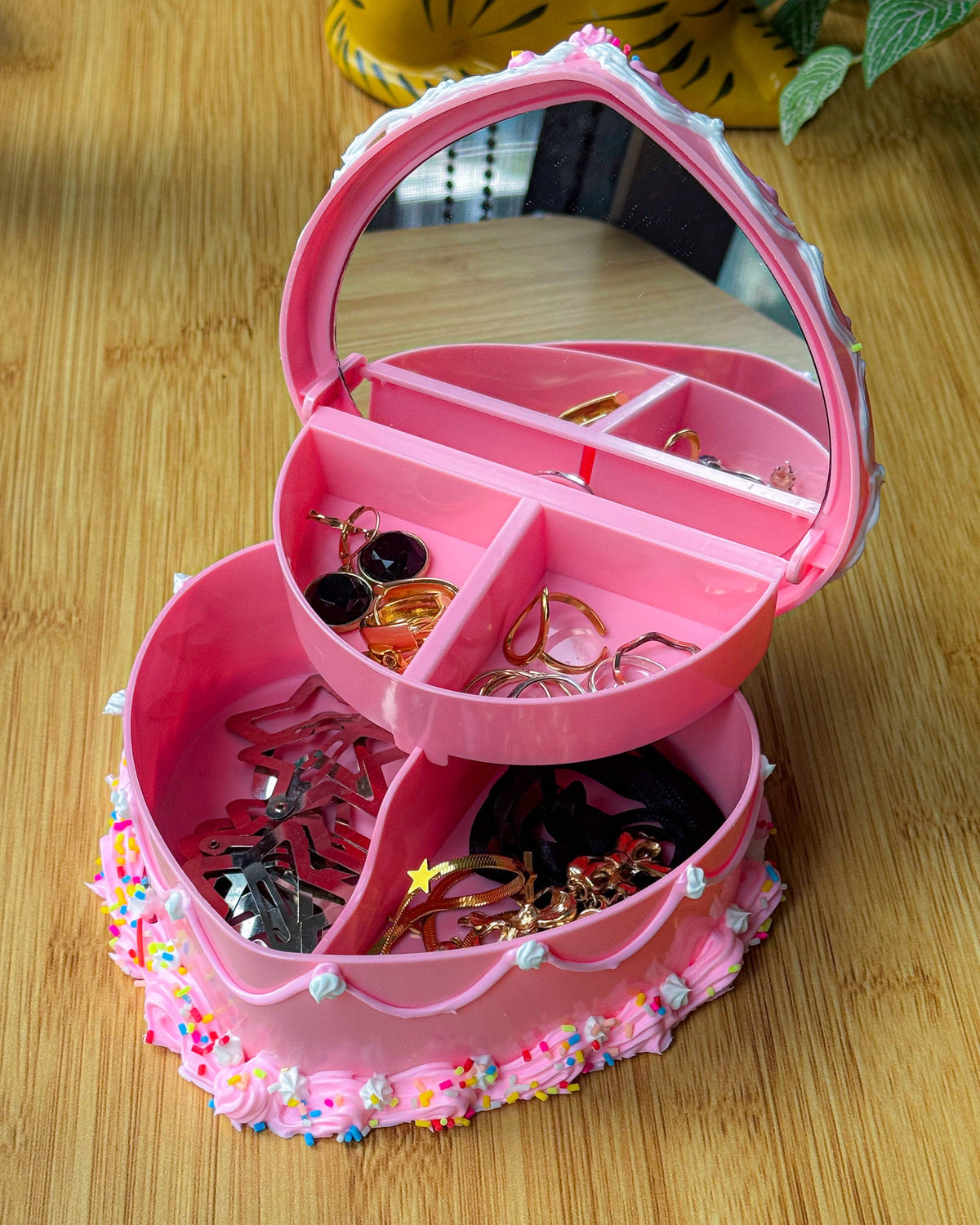 Pink jewelry organizer with compartments on a wooden surface