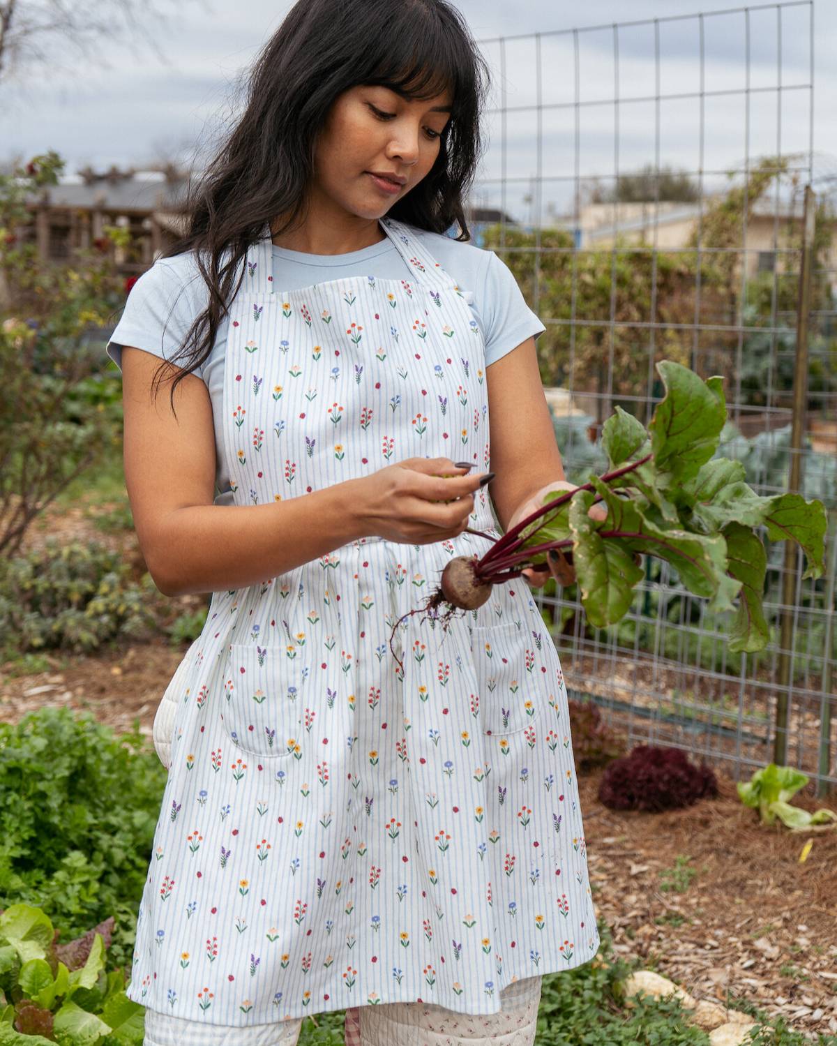 Young girl in a garden holding a bunch of fresh vegetables