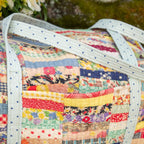 Colorful patchwork quilt with a white border, featuring various patterns and colors.
