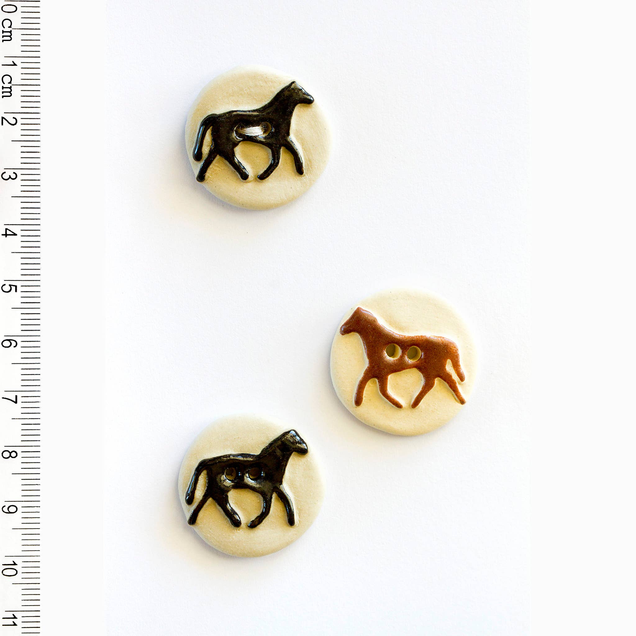 Three buttons with horse designs on a white background