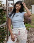 Person wearing a light blue cropped baby  t-shirt with 'Inner Grandma' text, standing outdoors.