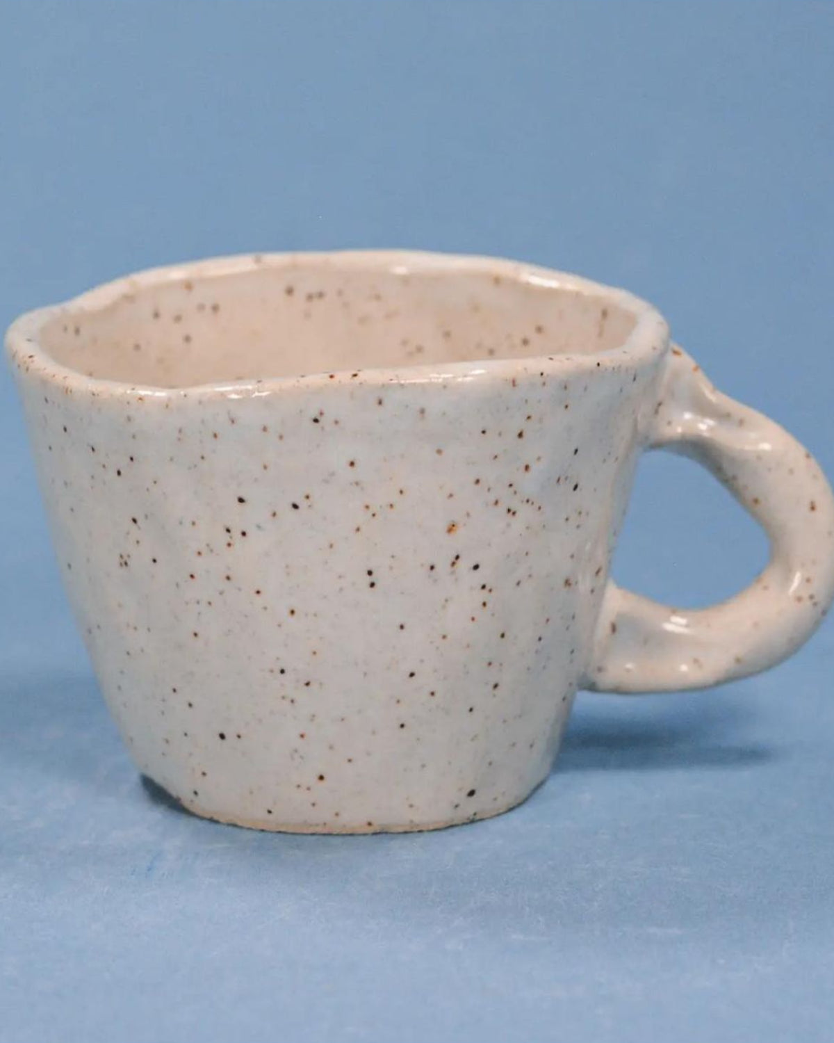 Speckled ceramic mug on a blue background