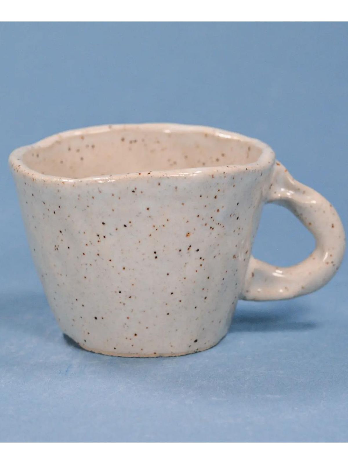 back view of speckled coffee cup on a blue backroud