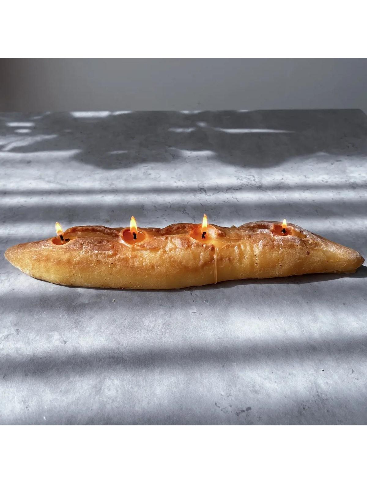 Bread with small candles on a textured surface