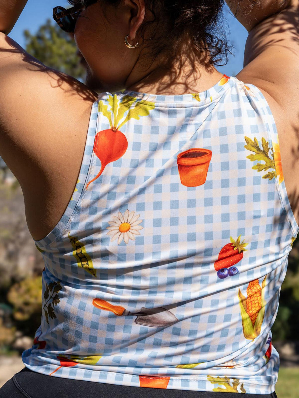 Person wearing a sleeveless shirt with garden-themed design outdoors