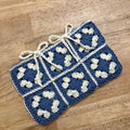 Blue and white crocheted blanket on a wooden surface