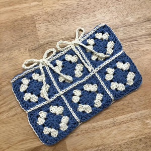 Blue and white crocheted blanket on a wooden surface