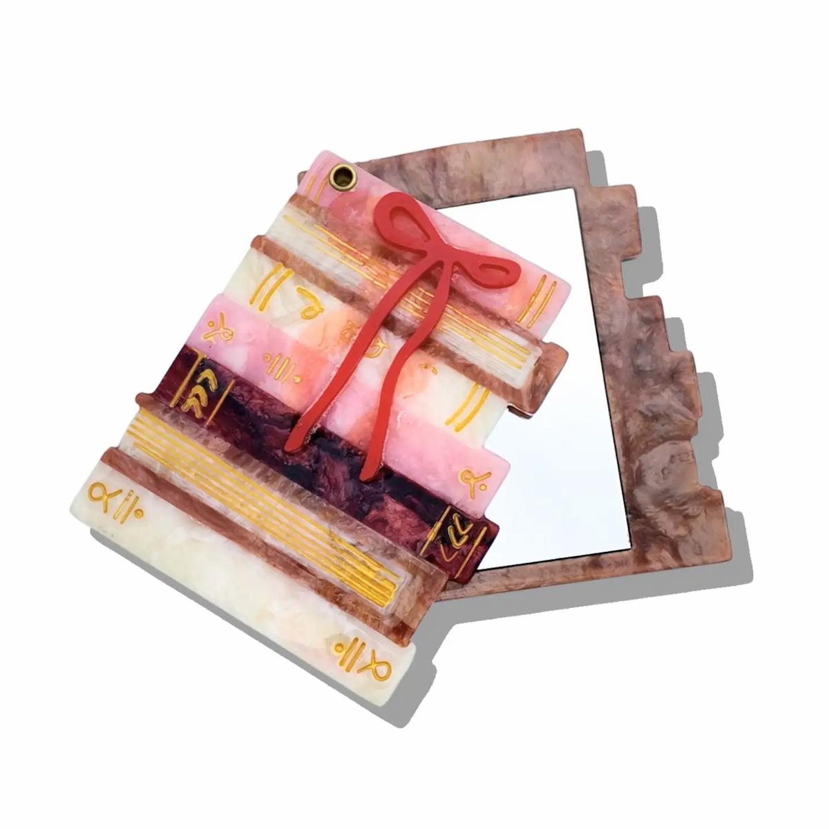 Decorative item resembling a stack of books with a red ribbon on a white background