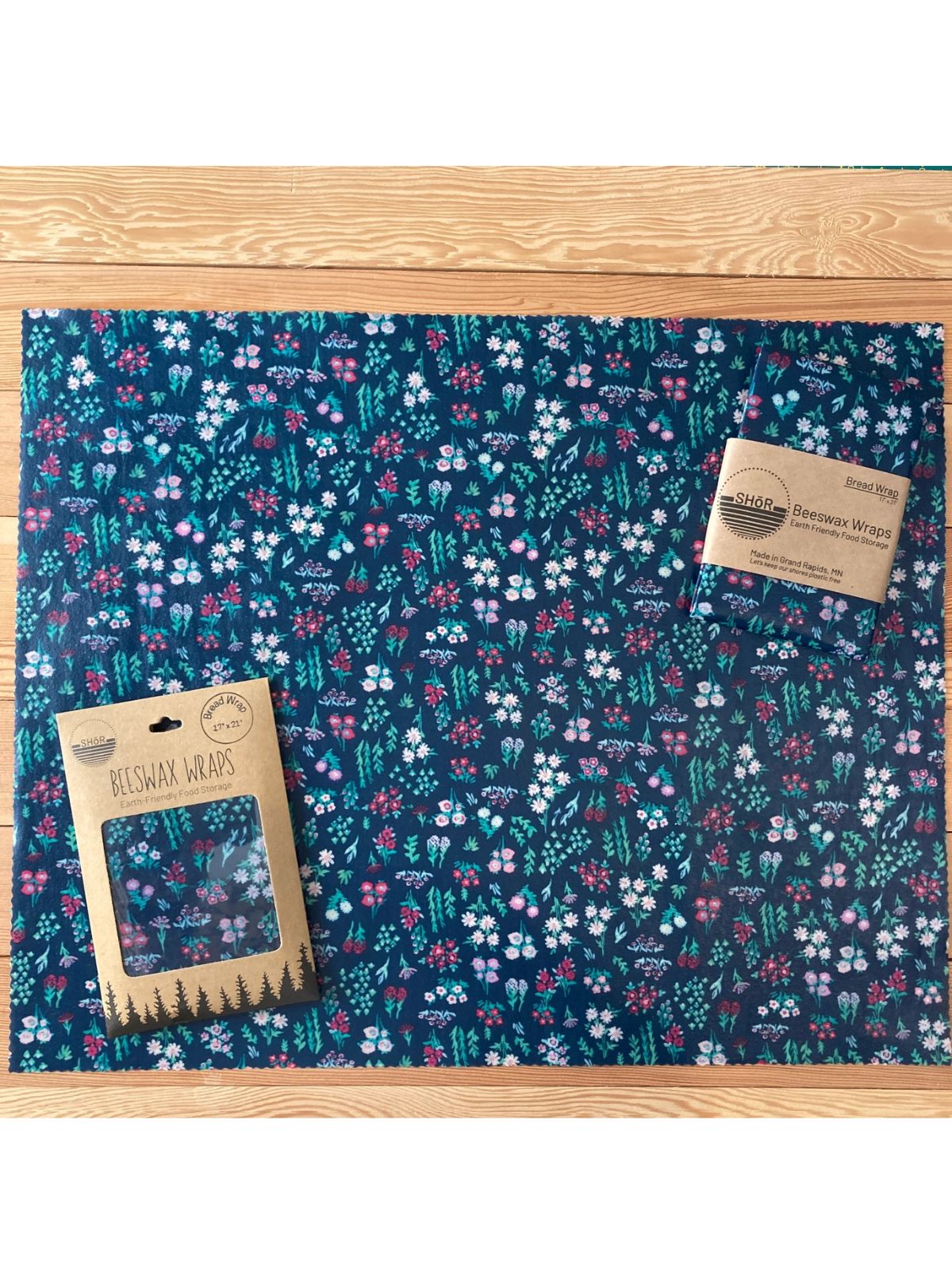 Floral-patterned reusable wrap on a wooden surface with packaging.