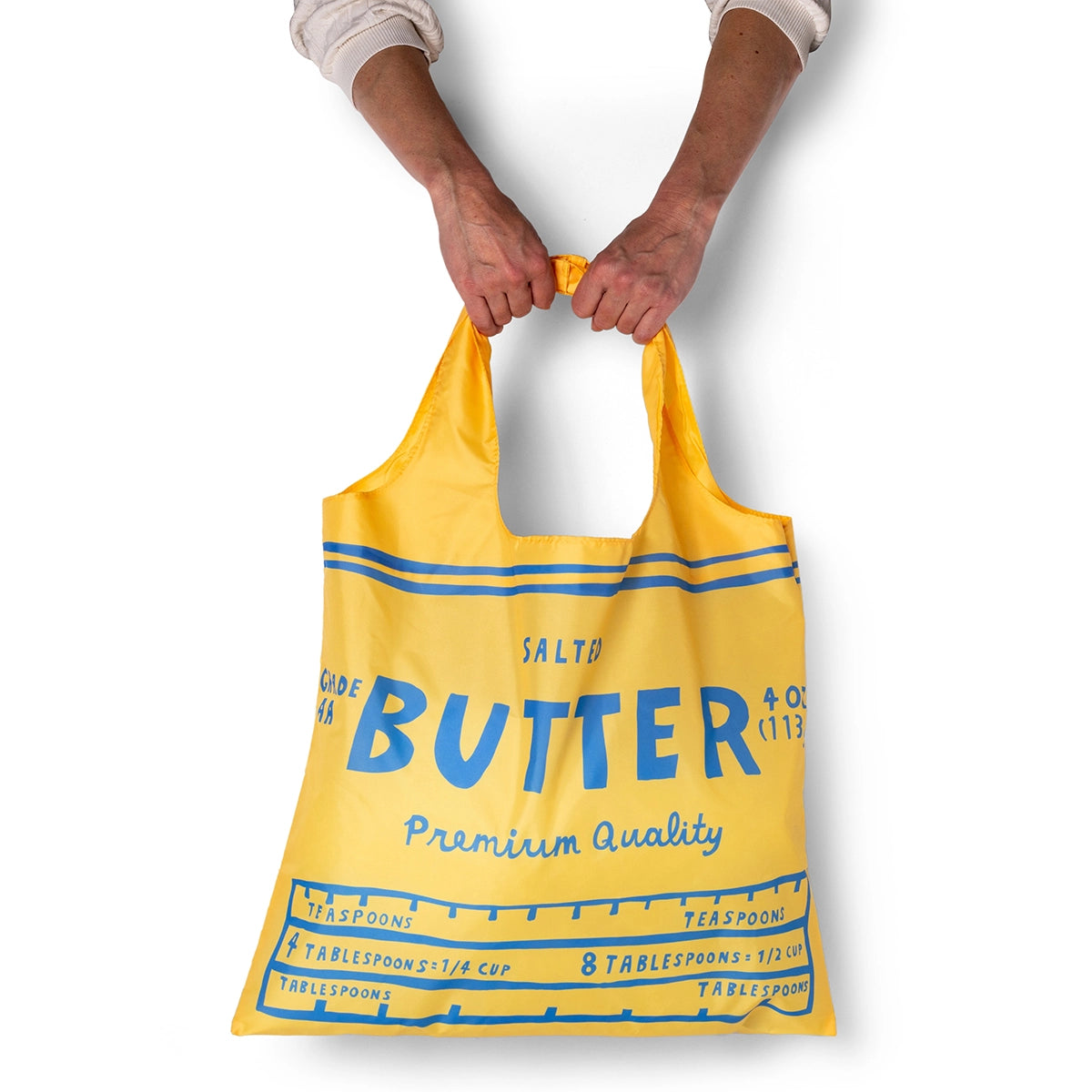 Yellow reusable bag with blue text held by a person on a white background