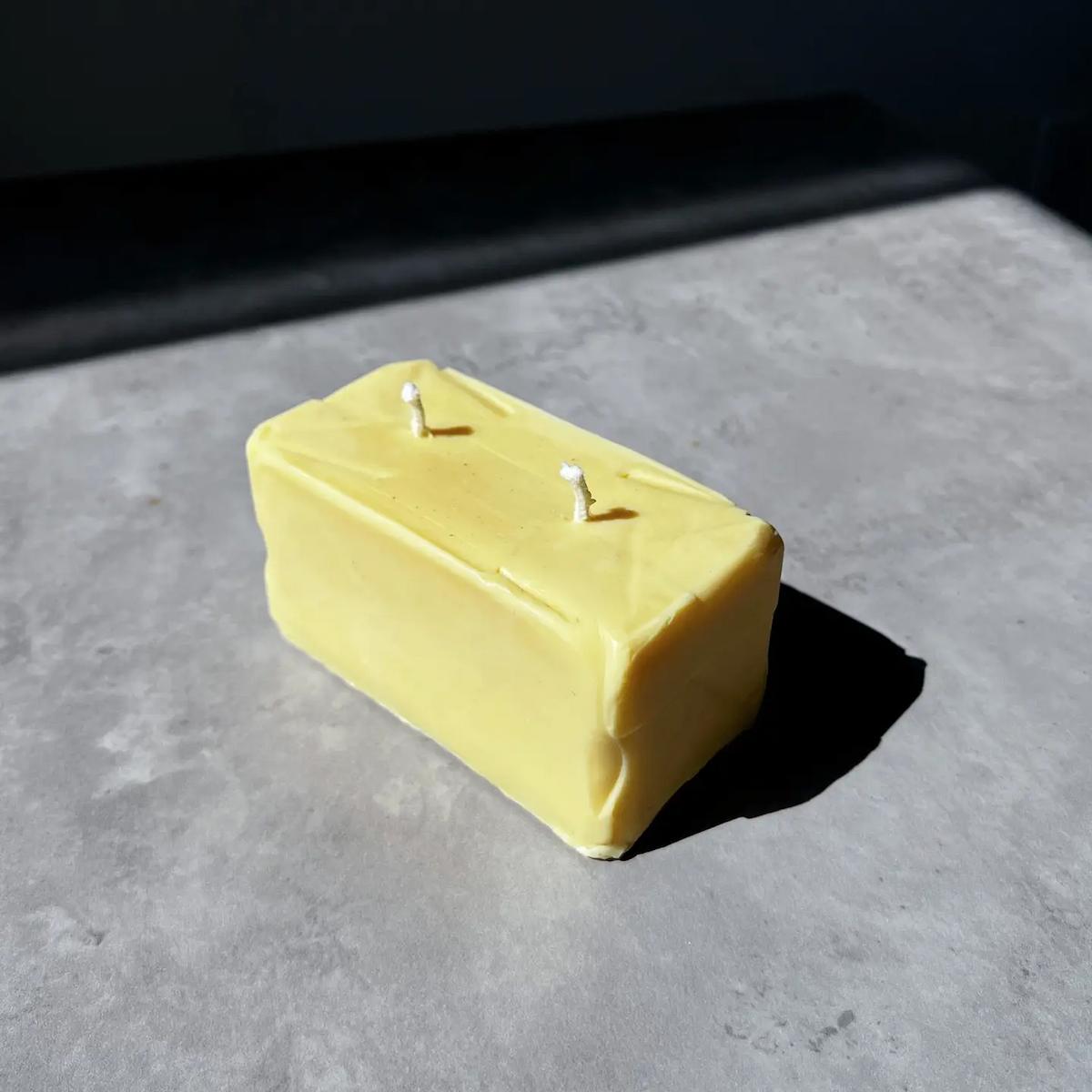 Rectangular yellow candle on a gray surface with a dark background