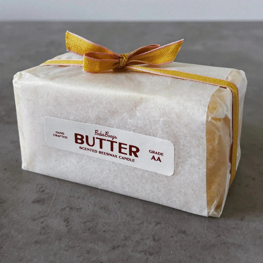 Beeswax candle wrapped in paper with a yellow ribbon on a gray surface