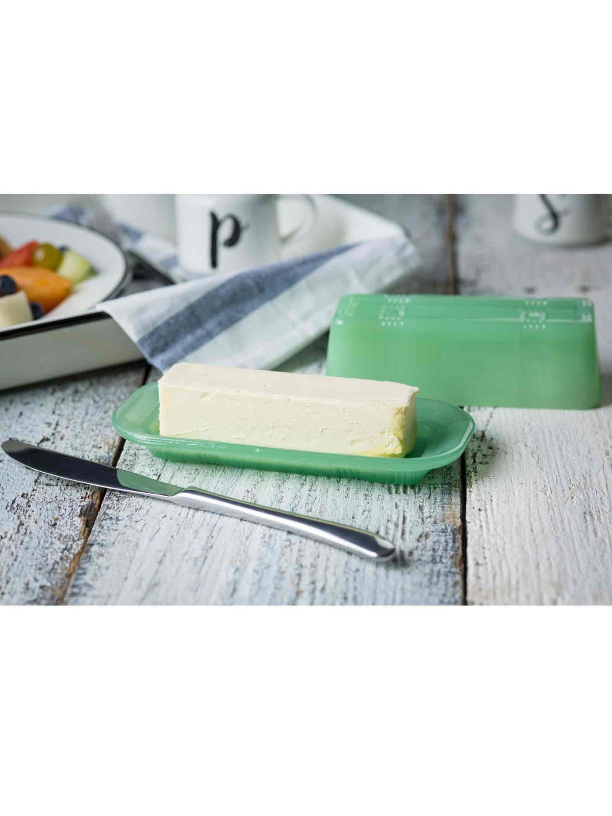 Butter on a green plate with a knife on a wooden surface