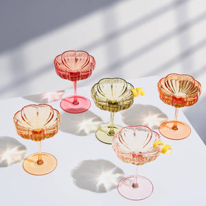 Set of colorful glass cocktail glasses on a light surface with soft shadows.