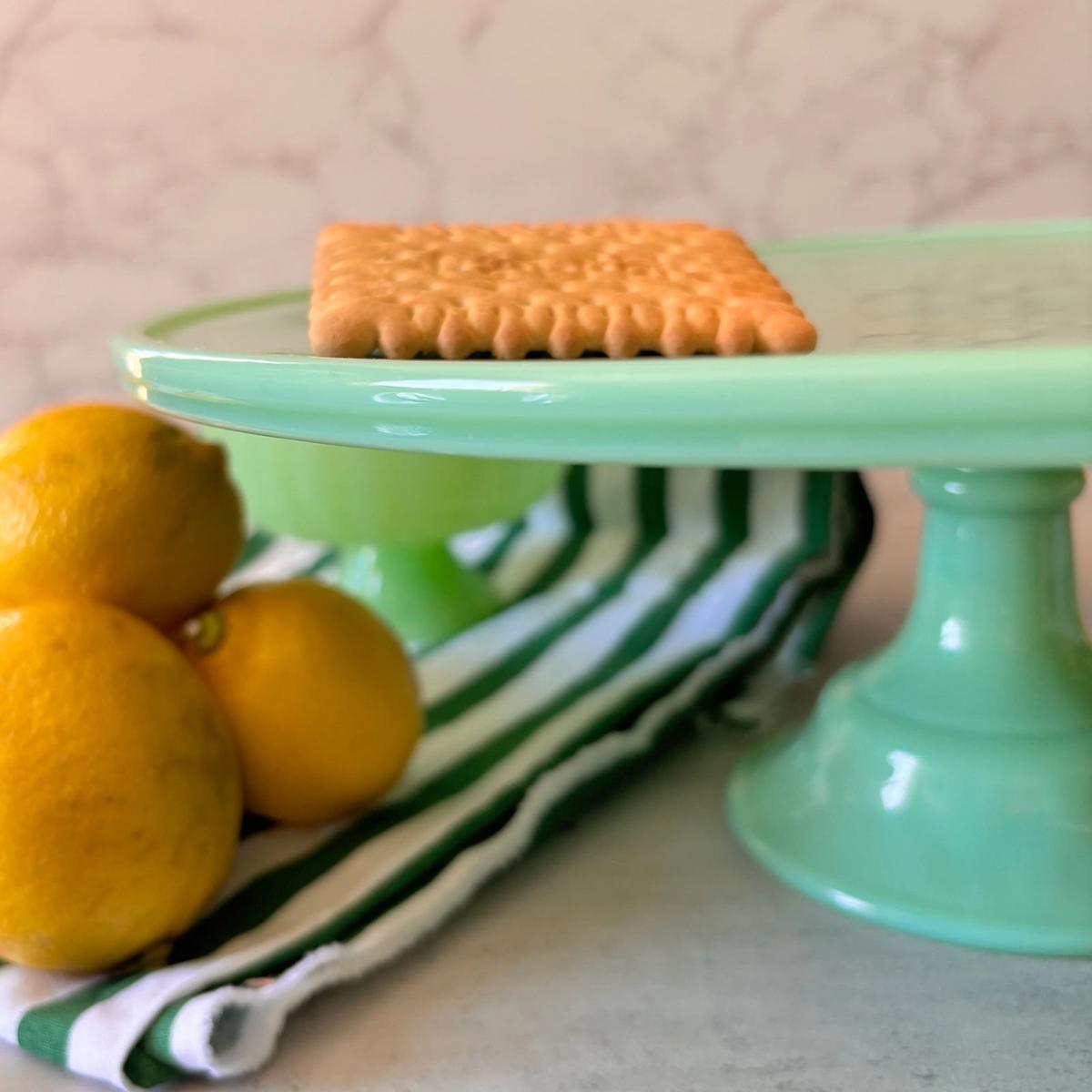Green cake stand with a cookie and lemons on a striped cloth