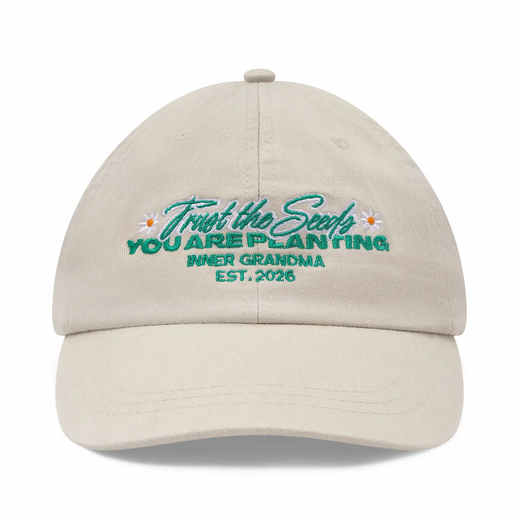 Beige cap with embroidered text and floral designs on a white background