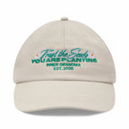 Beige cap with embroidered text and floral designs on a white background