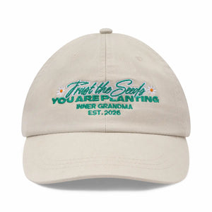 Beige cap with embroidered text and floral designs on a white background