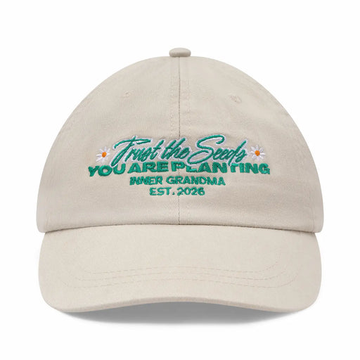 Beige cap with embroidered text and floral designs on a white background