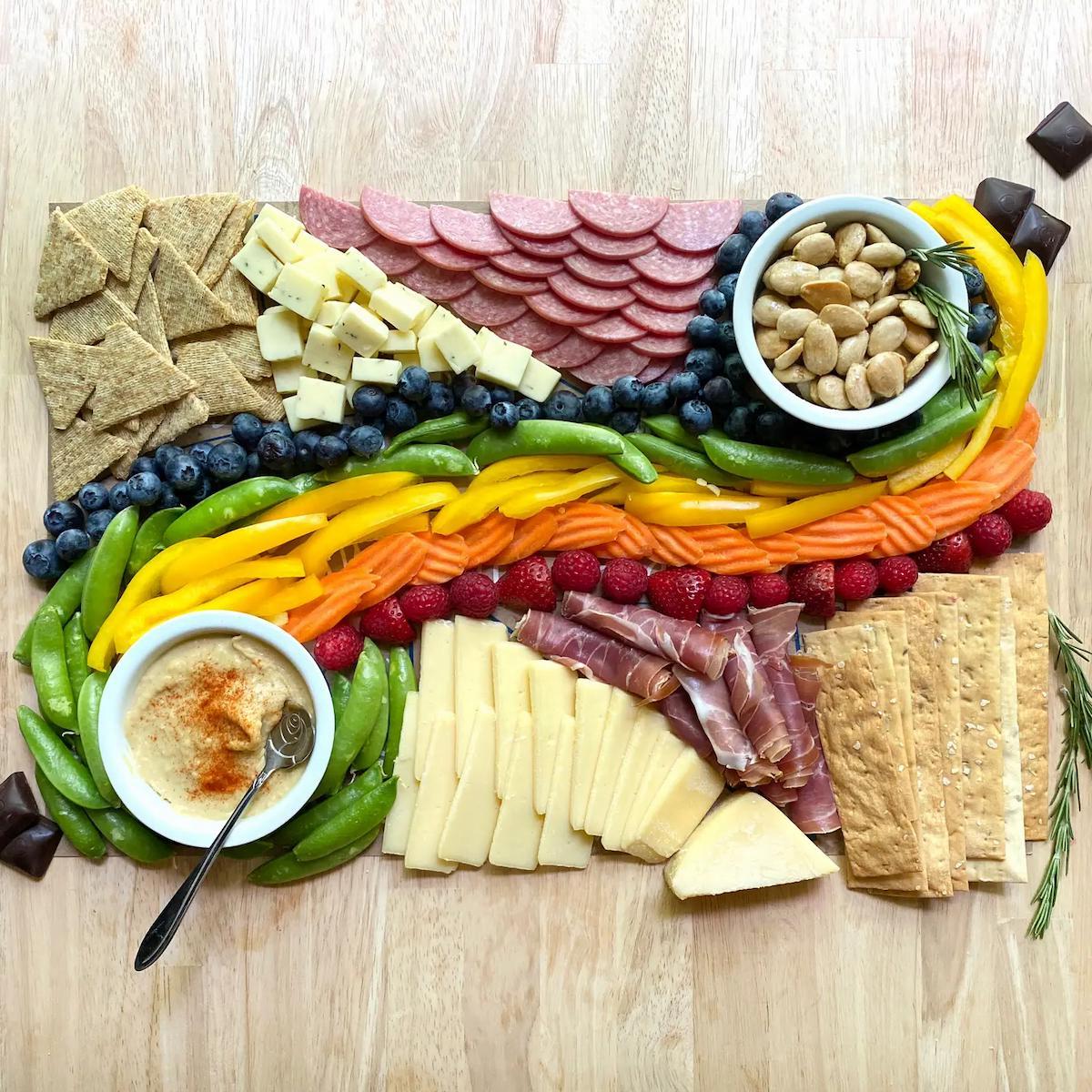 Colorful charcuterie board shaped like a fish on a wooden surface.