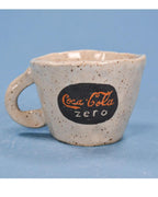 Speckled ceramic mug with Coca-Cola Zero logo on a blue background