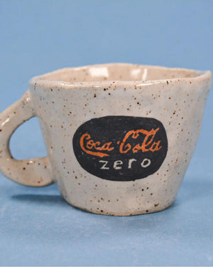 Speckled ceramic mug with Coca-Cola Zero logo on a blue background