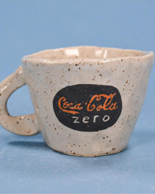 Speckled ceramic mug with Coca-Cola Zero logo on a blue background