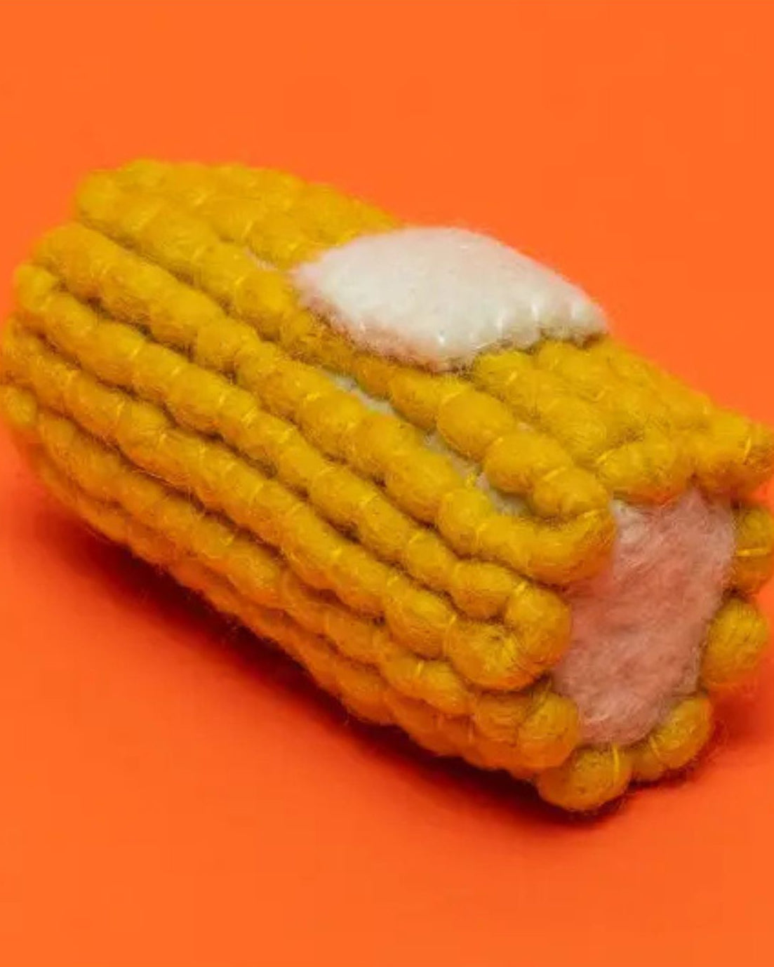 Corn-shaped toy with a white kernel on an orange background