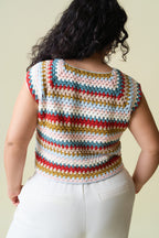 Back of person wearing a colorful crochet top against a plain background