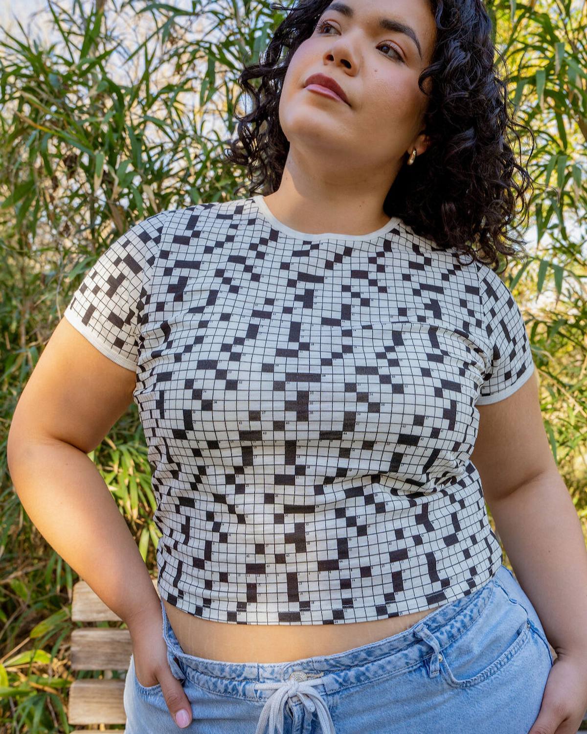 Woman wearing a black and white patterned crop top with blue jeans outdoors.