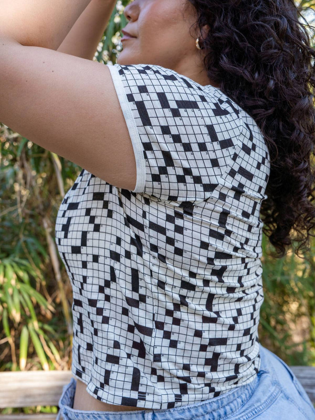 Person wearing a black and white geometric patterned top with a blurred natural background