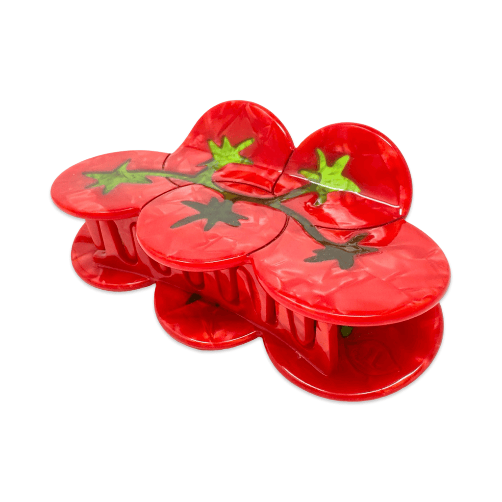 Red plastic tomato-shaped hair claw clip with green stems on a white background