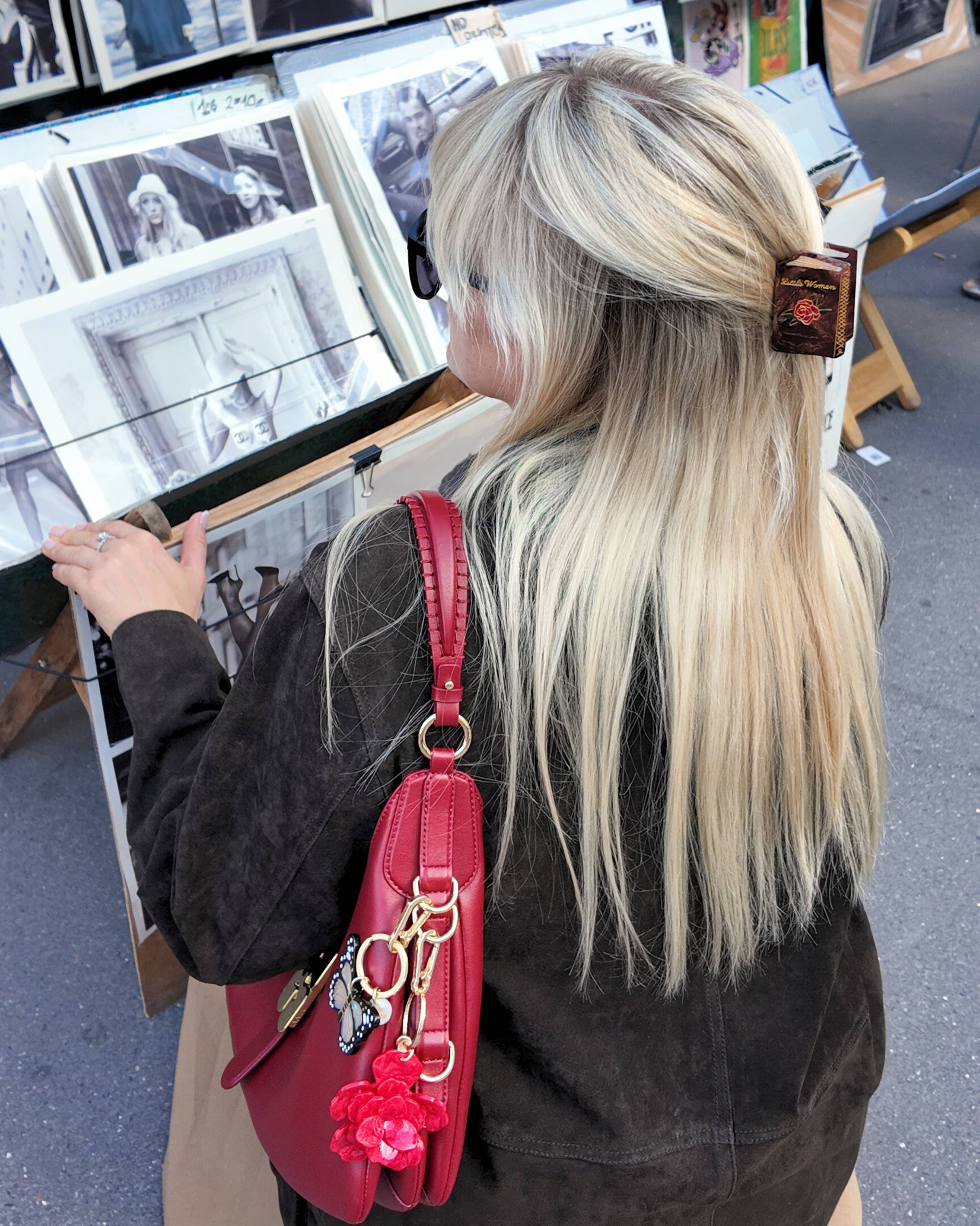 Person with long blonde hair wearing a Little Women hair clip looking at art 