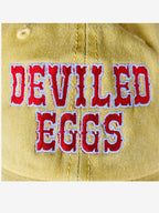 Close up of yellow cap with 'Deviled Eggs' embroidered in red 