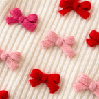 Knitted bows in red and pink on a textured beige background