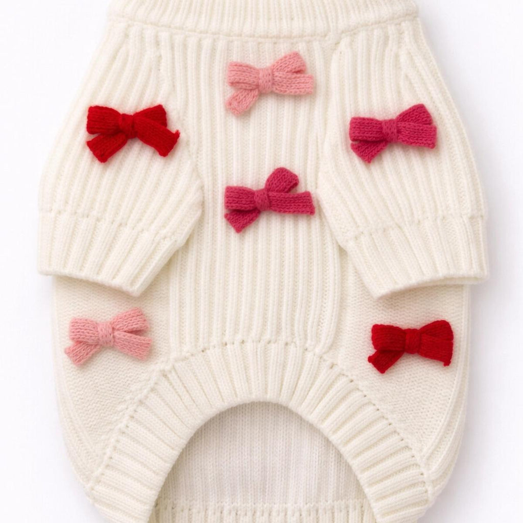 White knitted romper with red and pink bows on a white background