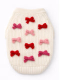 White knitted pet sweater with red and pink bow decorations on a white background